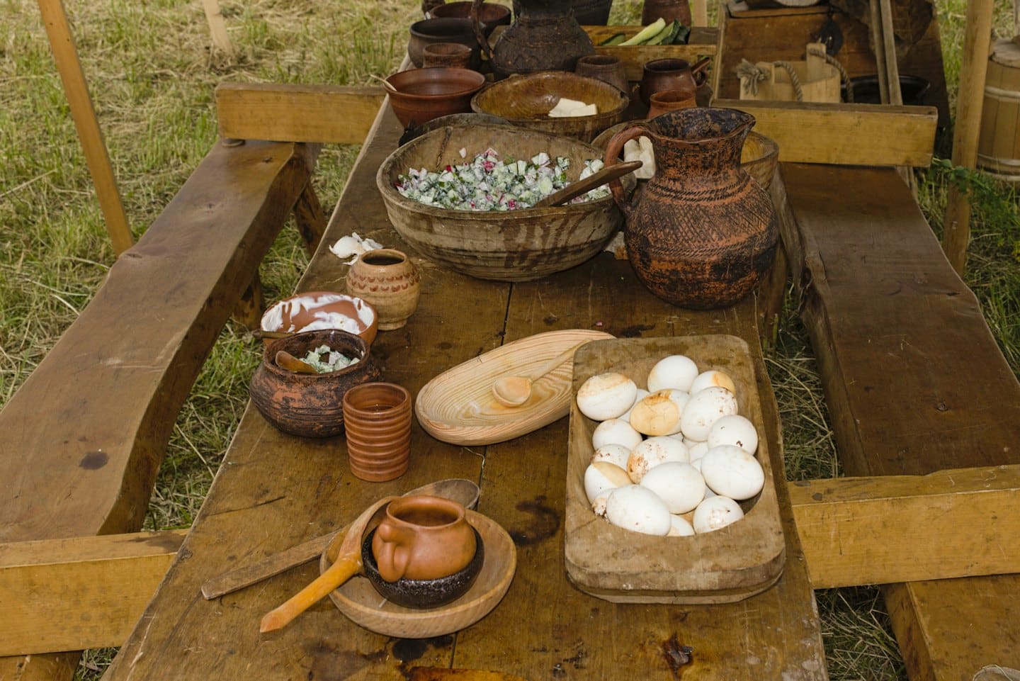 Comida tradicional y huevos dispuestos sobre una larga mesa rústica de madera.